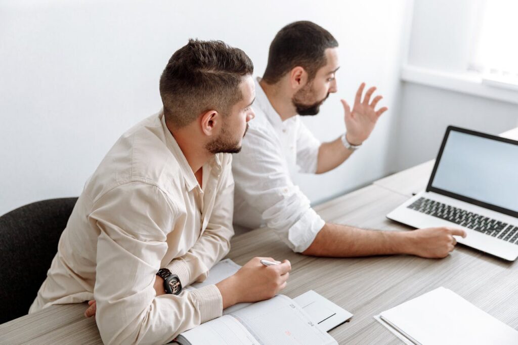 pexels photo 5257191 Two adult men collaborating in a modern office setting, discussing ideas with a laptop.