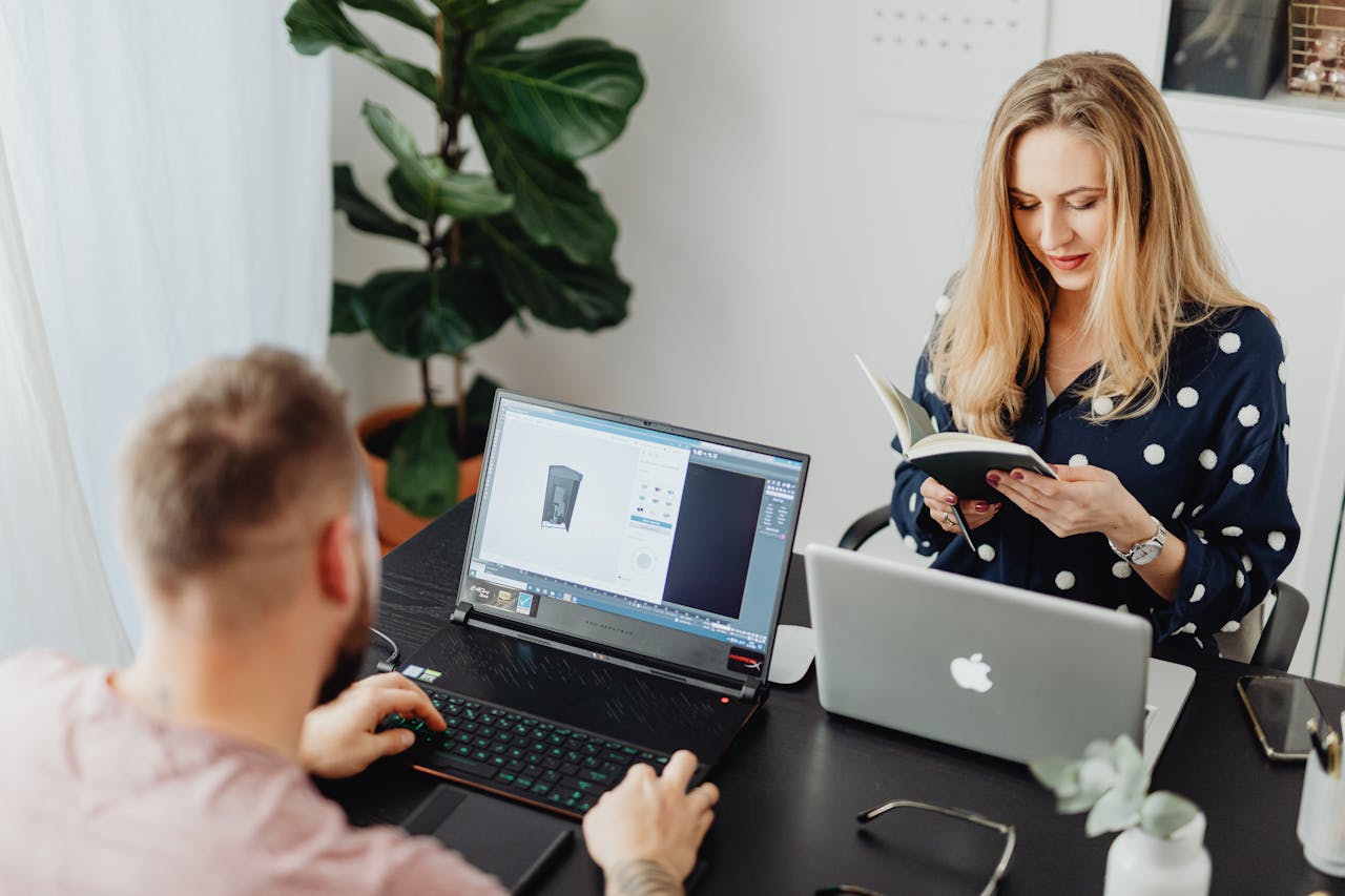 About Professional coworkers collaborating in a modern office setting with laptops and a notebook.